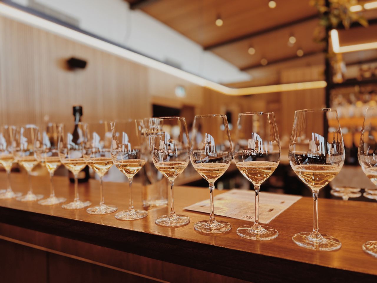 Elegant white wine tasting setup with glasses lined up on a bar counter, perfect for events.